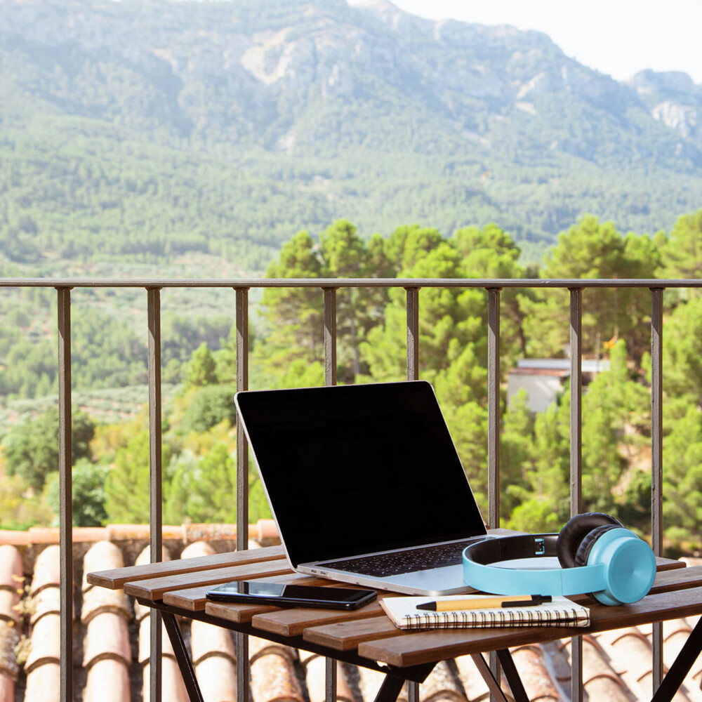 laptop-blue-headsets-notebook-cellphone-table-balcony-with-beautiful-view