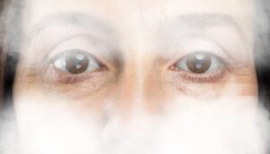 középkorú nő szemei a láthatatlanságot jelképező ködbe burkolva