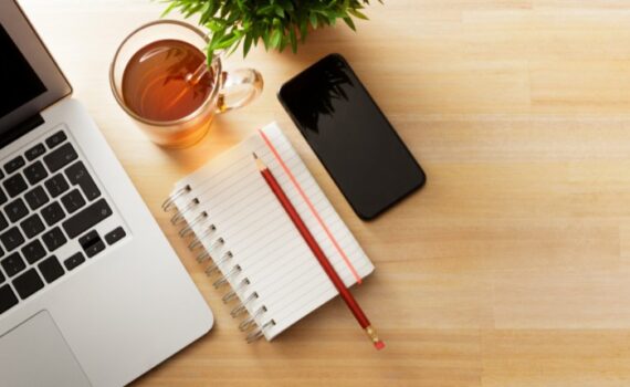 otthoni iroda kellékei jegyzetfüzet ceruza okostelefon laptop és egy csésze tea