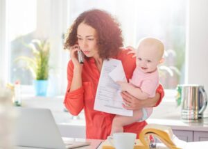 telefonáló otthon dolgozó dolgozó anya kisbabával a karjában