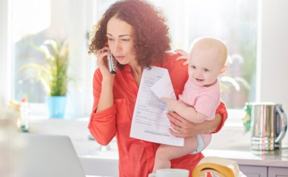 telefonáló otthon dolgozó dolgozó anya kisbabával a karjában