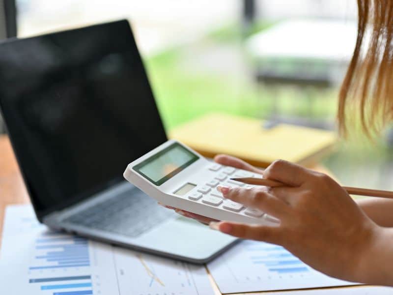 pénzügyi asszisztens számológéppel a kezében laptop előtt